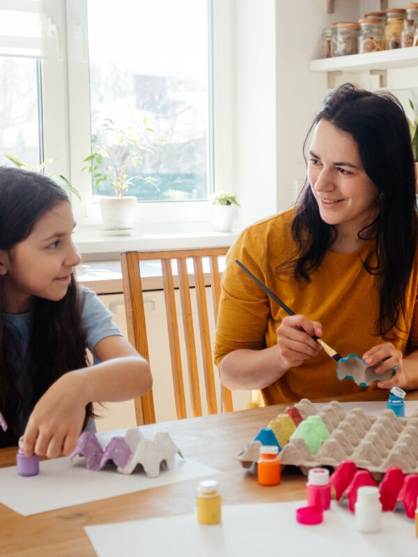 Engelse leraar en kind werken samen aan creatief project, Engels leren met de CLIC-methode voor kinderen.
